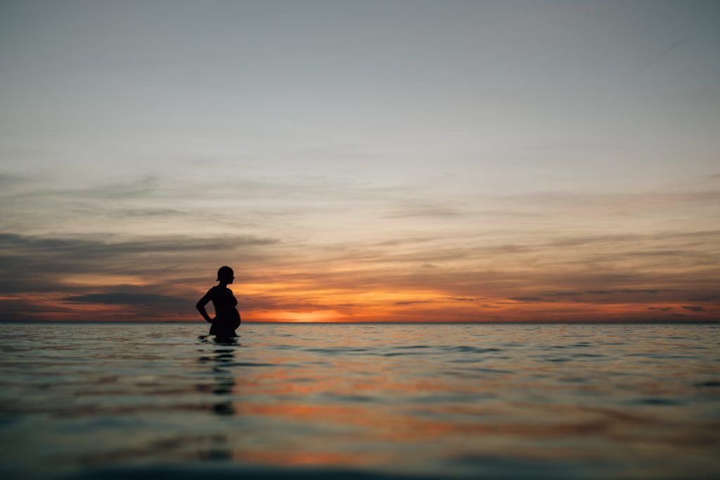 silhouette of pregnant woman in water at sunset during beach maternity photos, And So I Don't Forget Photography