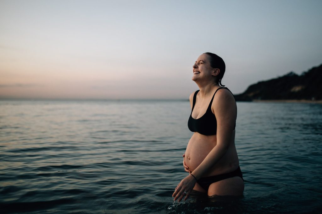 Pregnant women in bikini laughing during beach maternity photos, And So I Don't Forget Photography