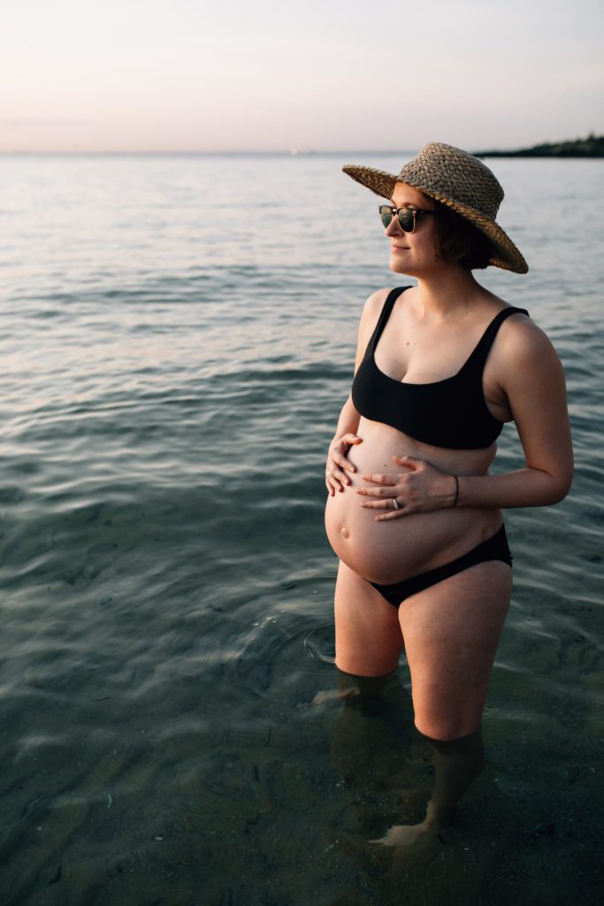 pregnant woman in black bikini and hat during beach maternity photos, And So I Don't Forget Photography