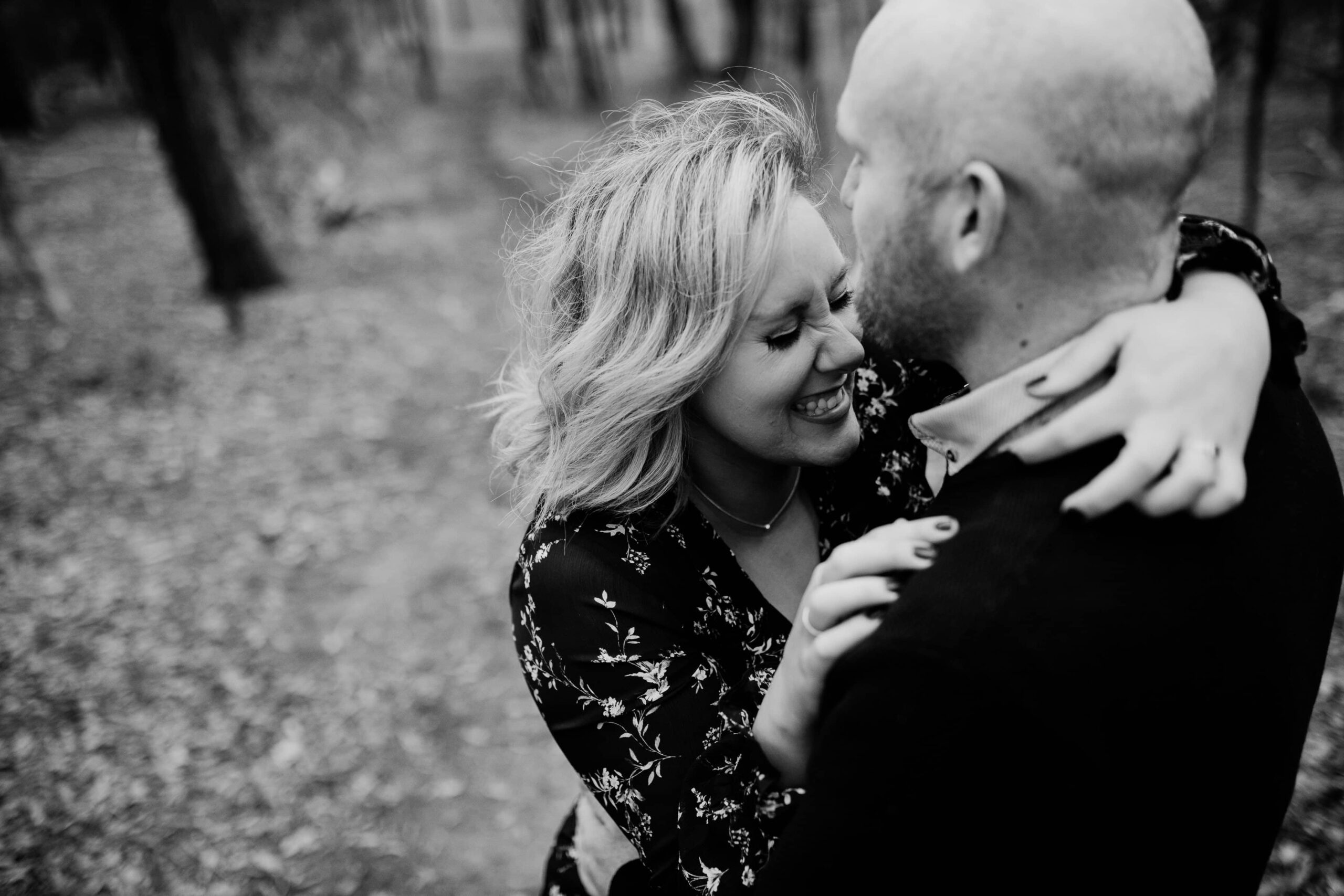 black and white image of woman laughing with eyes closed as she hugs fiancé during melbourne engagement photo session in bushland