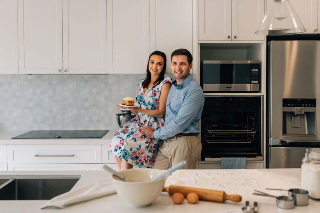 couple hugging in kitchen with bun in the oven from pregnancy announcement