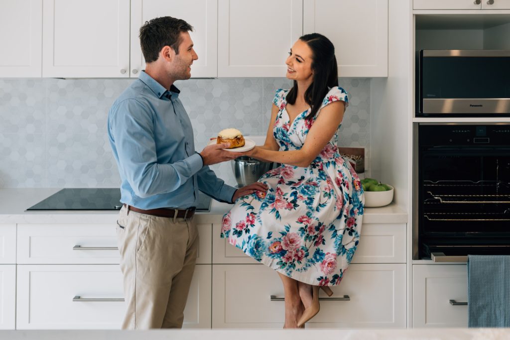 woman handing bun to her husband from bun in the oven pregnancy announcement photography session