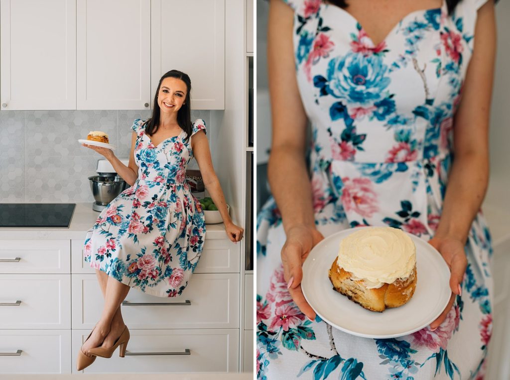 woman in floral dress sitting on kitchen bench with bun, funny pregnancy announcement photography