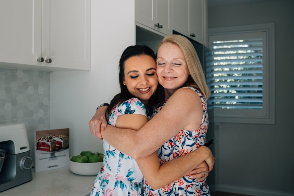 grandmother-to-be hugging mother-to-be after bun in the oven pregnancy announcement