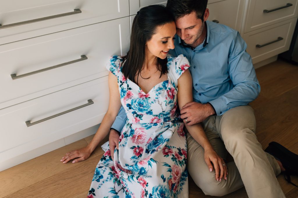 funny pregnancy announcement ideas for photography session, man and woman snuggled together on kitchen floor