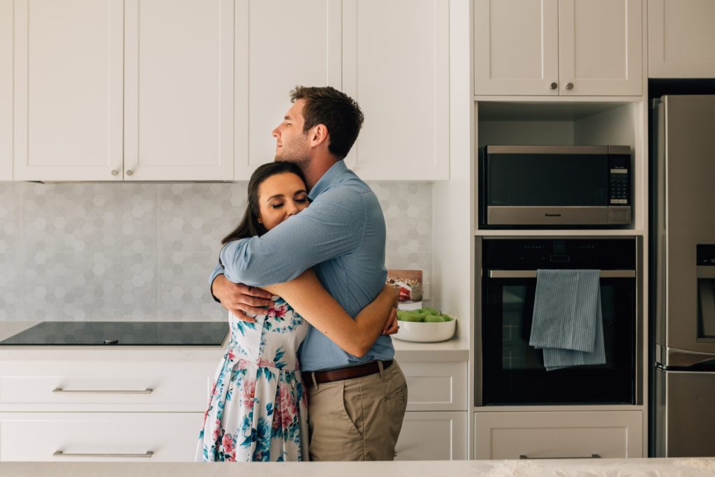 husband and wife embracing, bun in the oven pregnancy announcement photography session