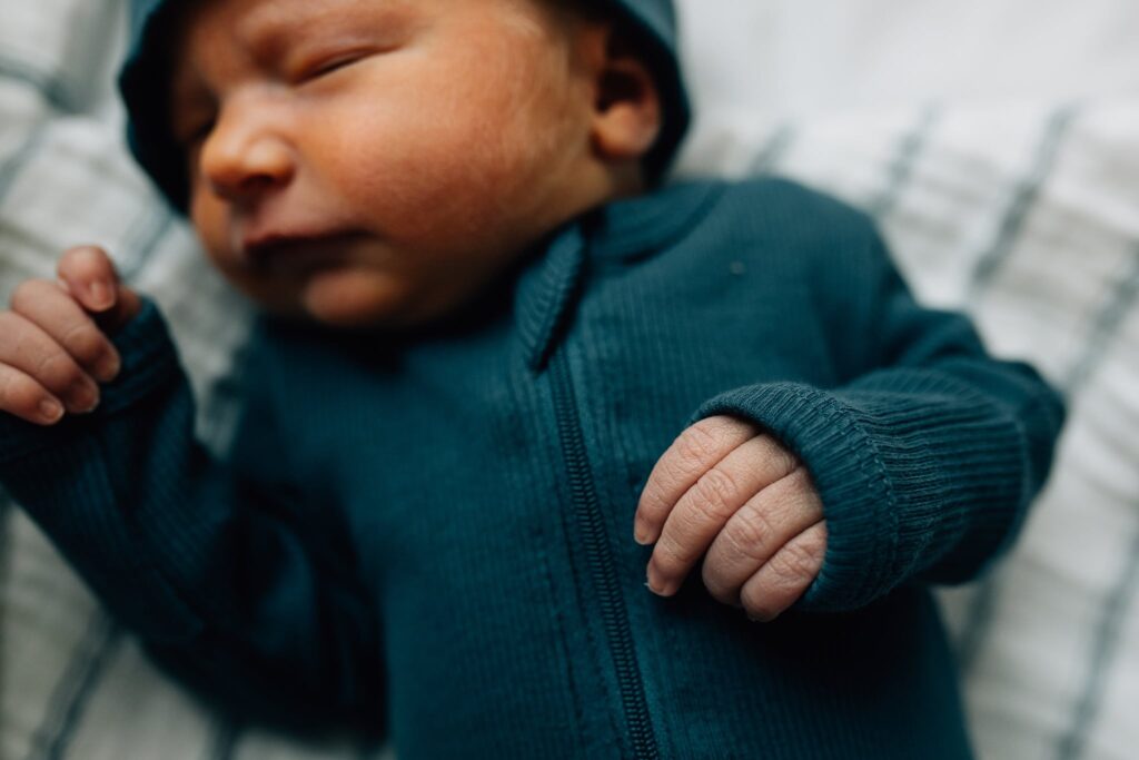 Sleeping baby in blue outfit, focusing on his hand. Fresh 48 at St Vincent's Private