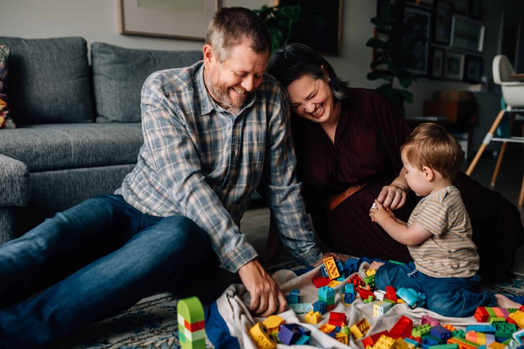 Mum laughing and leaning on Dad while son plays Duplo, value of photography, especially plus size family photos